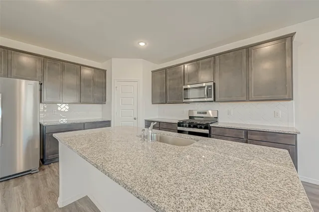 a kitchen with stainless steel appliances granite countertop a sink stove and refrigerator