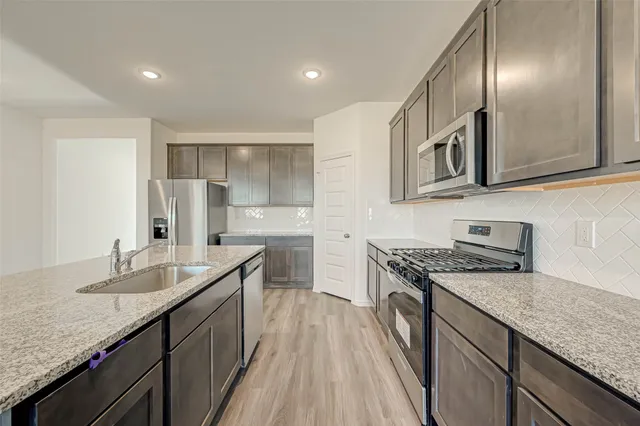 a kitchen with granite countertop stainless steel appliances a sink stove top oven and cabinets