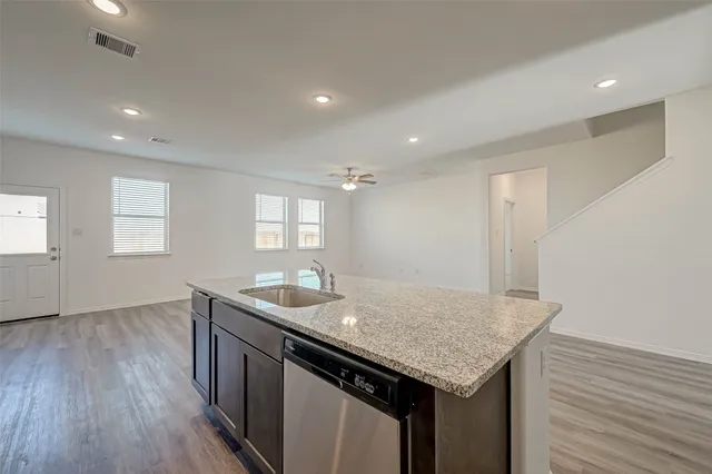 a kitchen with granite countertop kitchen island a sink appliances and wooden floor