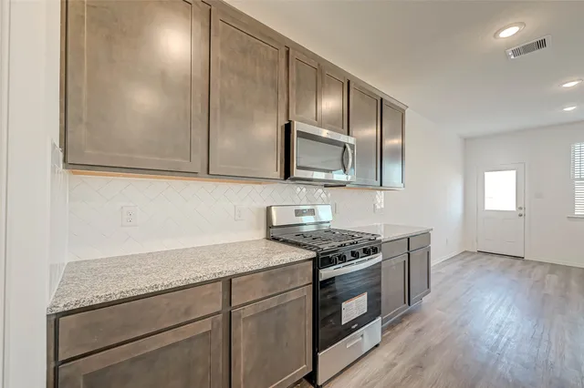 a kitchen with stainless steel appliances granite countertop a sink stove and cabinets