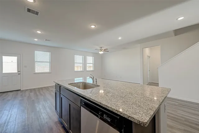 a kitchen with granite countertop kitchen island stainless steel appliances a sink stove and wooden floor