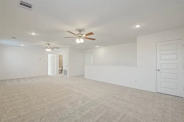 an empty room with a chandelier fan and windows