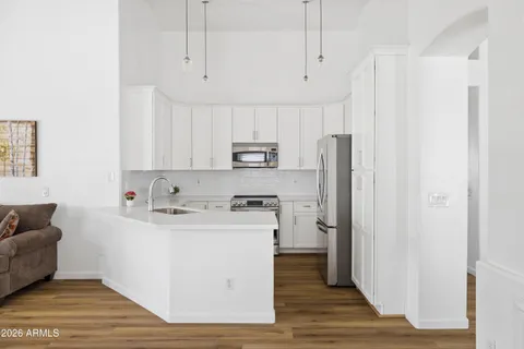 a kitchen with stainless steel appliances granite countertop a refrigerator a stove and white cabinets with wooden floor