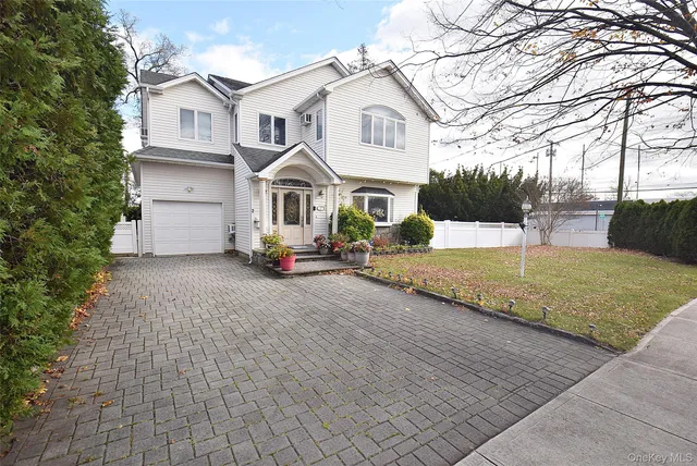 a view of a white house with a yard and large trees