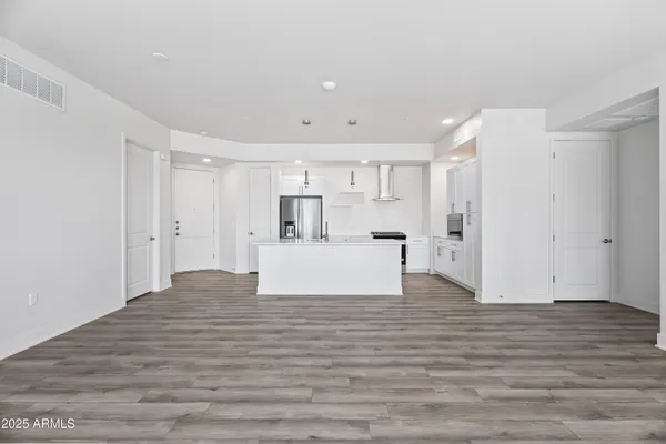 a kitchen with stainless steel appliances granite countertop a stove top oven a sink with white cabinets and wooden floor