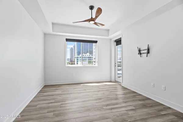 a view of empty room with wooden floor and fan