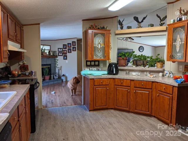 a kitchen with stainless steel appliances granite countertop wooden cabinets a stove a sink and a wooden floor