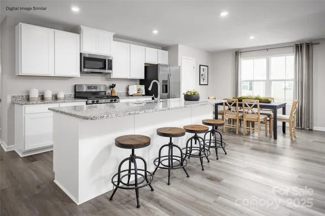 a kitchen with stainless steel appliances granite countertop a stove a refrigerator a microwave a dining table and chairs cabinets with wooden floor