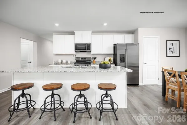 a kitchen with stainless steel appliances granite countertop a table chairs microwave and refrigerator