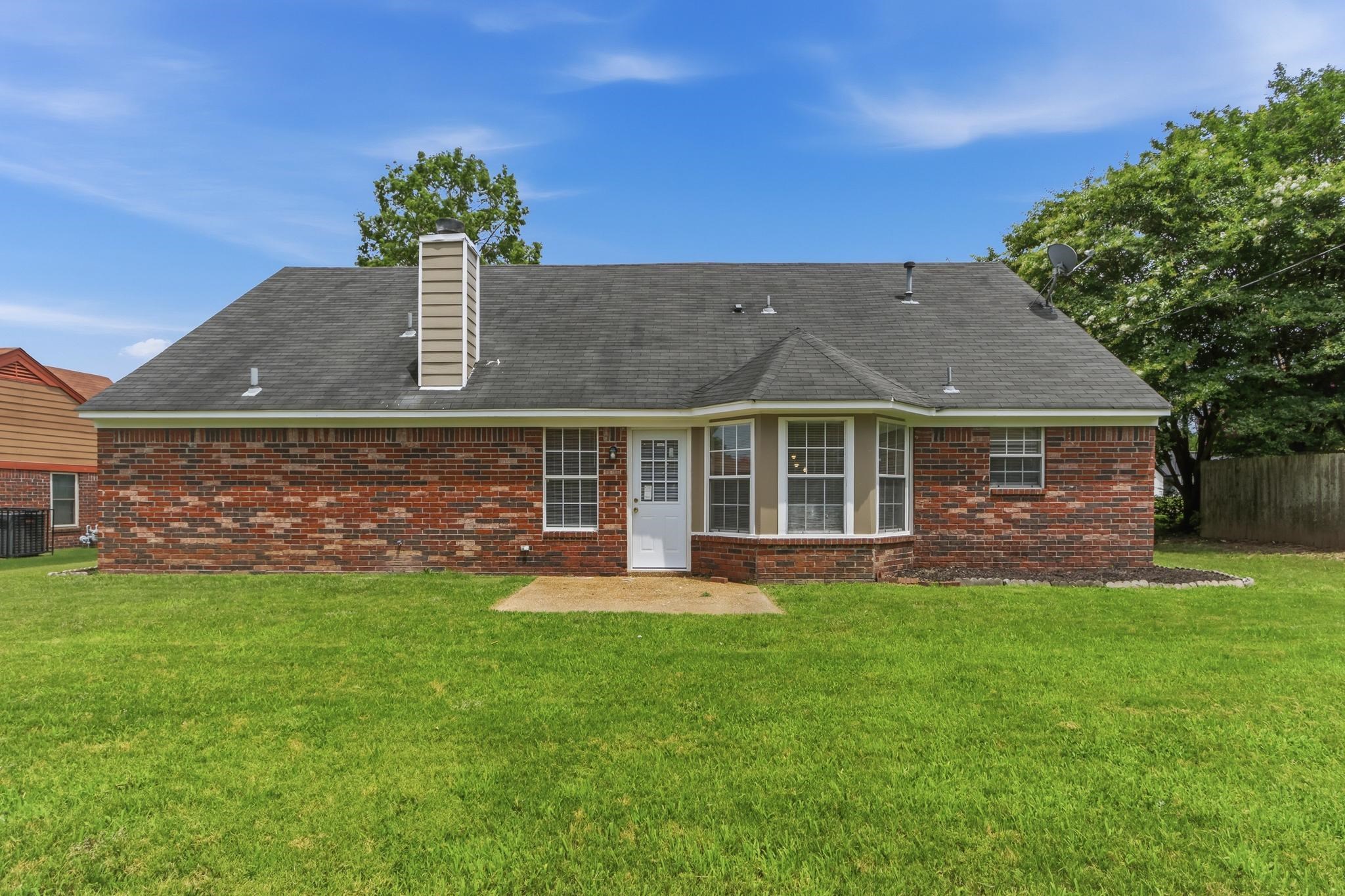 4101 Long Creek Road Memphis, TN 38125 - Photo 32 of 36 Expansive rear lawn featuring a brick exterior, a bay window, a concrete patio, and a chimney with vertical siding