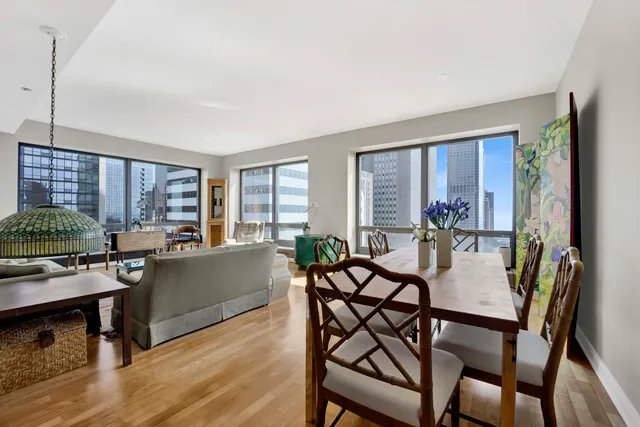a view of a dining room with furniture one side kitchen view and wooden floor