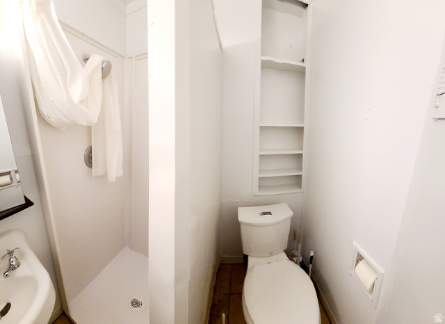 684 East 400 North Logan, UT 84321 - Photo 18 of 27 Compact bathroom featuring a stand-up shower with a showerhead, a wall-mounted sink with chrome faucet, a toilet, and built-in shelving