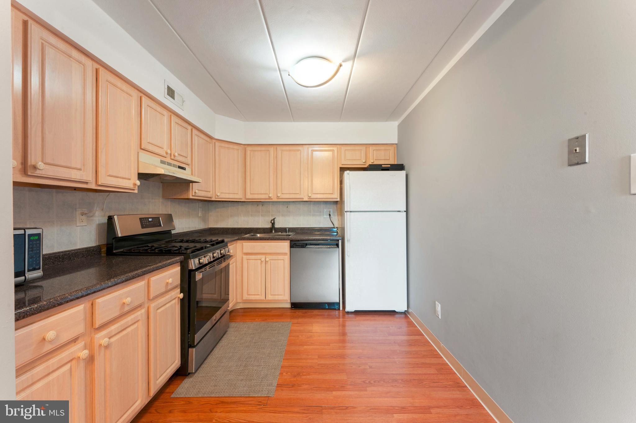 8940 Krewstown Road, Unit 204 Philadelphia, PA 19115 - Photo 11 of 23 a kitchen with stainless steel appliances granite countertop a refrigerator a sink dishwasher and a stove with wooden floor