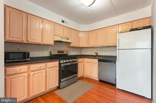 a kitchen with granite countertop wooden cabinets and white appliances