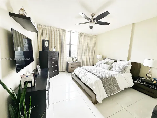 a bedroom with a bed a flat screen tv and a ceiling fan