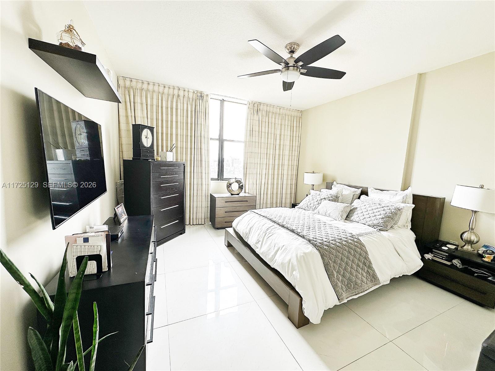 888 Douglas Road, Unit 1210 Coral Gables, FL 33134 - Photo 12 of 29 a bedroom with a bed a flat screen tv and a ceiling fan