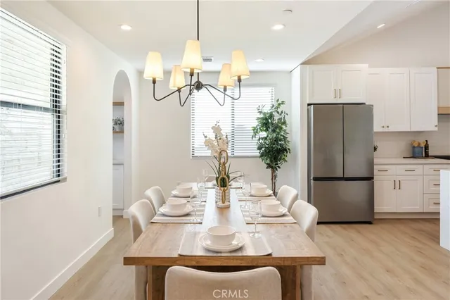 a kitchen with stainless steel appliances granite countertop a refrigerator a sink a stove a dining table and chairs