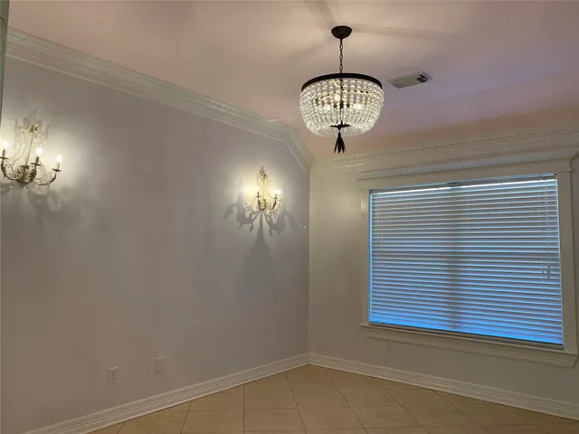 an empty room with a chandelier fan and wooden floor