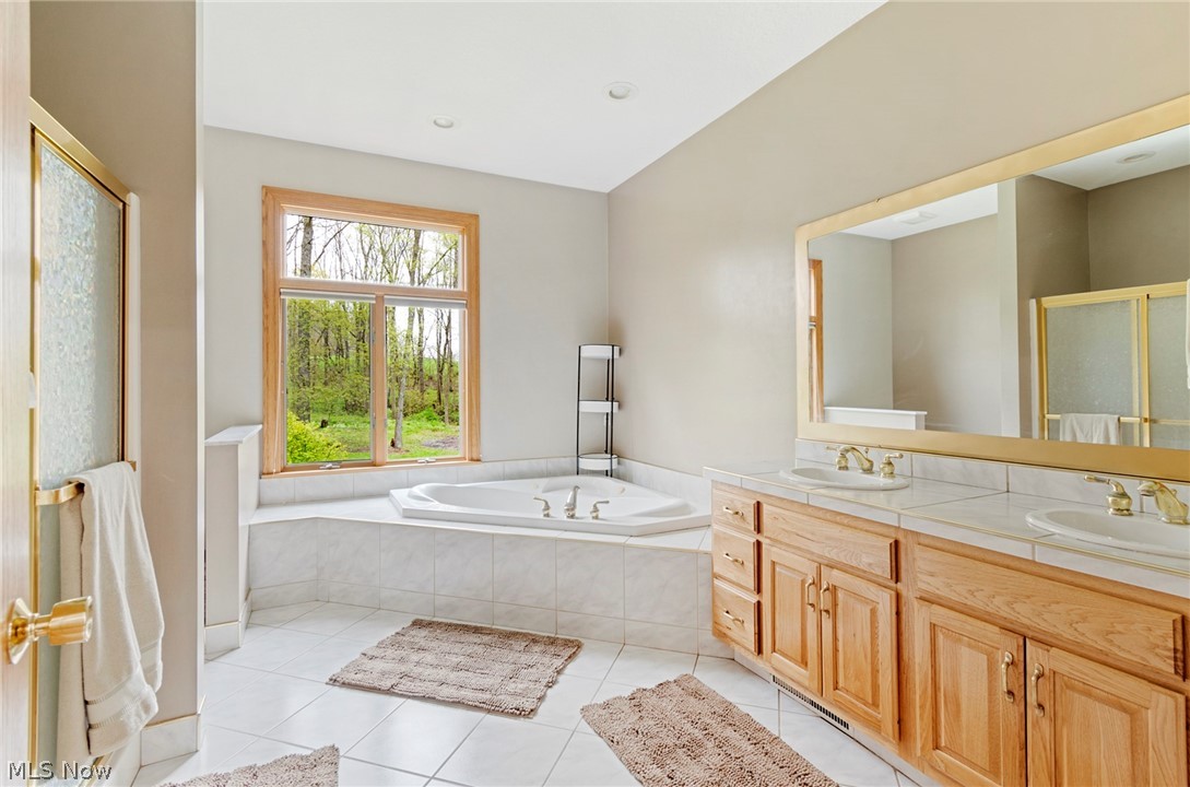 7435 South Raccoon Road Canfield, OH 44406 - Photo 28 of 47 Bathroom featuring double sink, a relaxing tiled bath, oversized vanity, and tile flooring