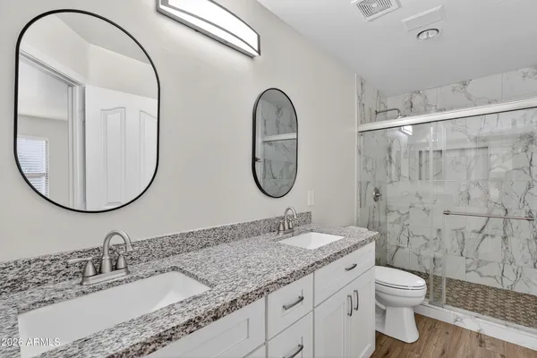 a bathroom with a granite countertop toilet a sink and a mirror