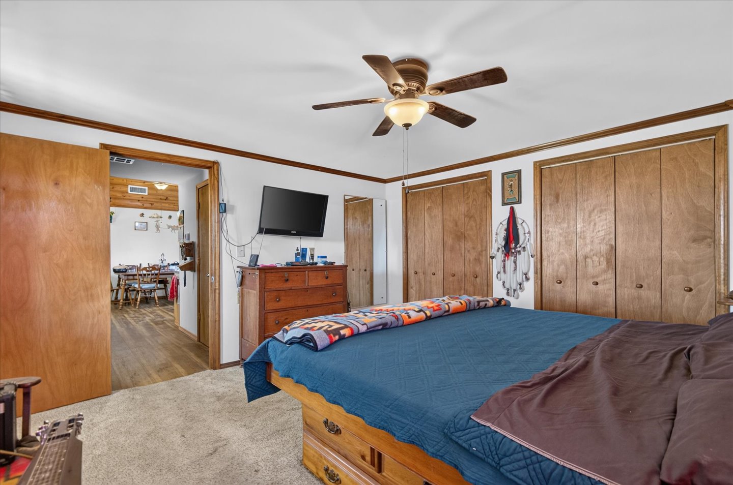 26115 4157th Road Nowata, OK 74048 - Photo 18 of 36 White walls with wood trim, ceiling fan with integrated lighting, and two sets of bi-fold closet doors