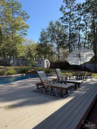 a view of a roof deck with table and chairs couches with wooden floor and fence