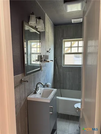 a bathroom with a bathtub sink and mirror