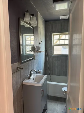 a bathroom with a bathtub sink and mirror