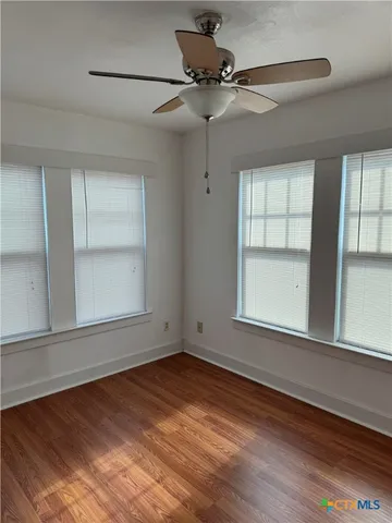 an empty room with wooden floor chandelier and windows