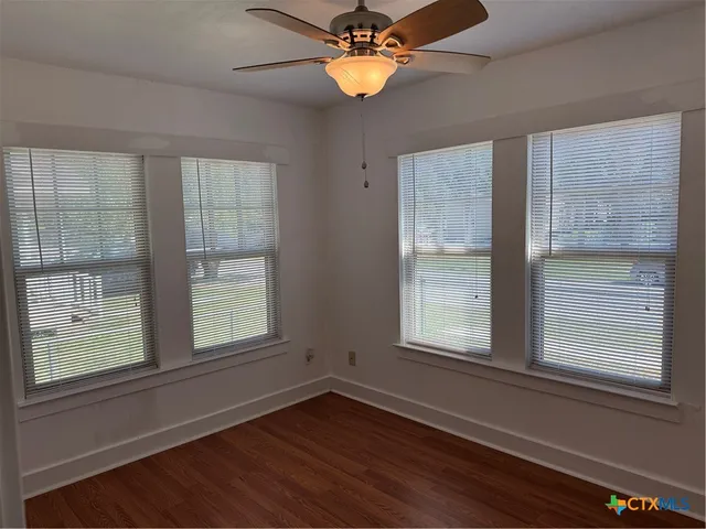 a view of empty room with wooden floor and window