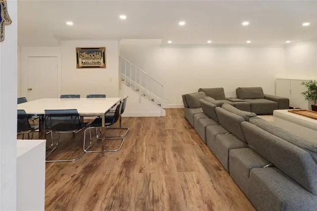 a living room with couches and kitchen view with wooden floor