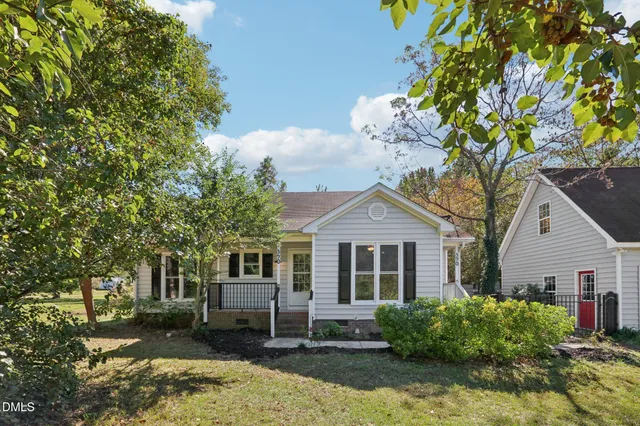 a front view of a house with a garden and trees