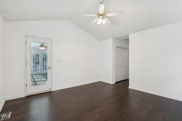 an empty room with wooden floor chandelier fan and windows