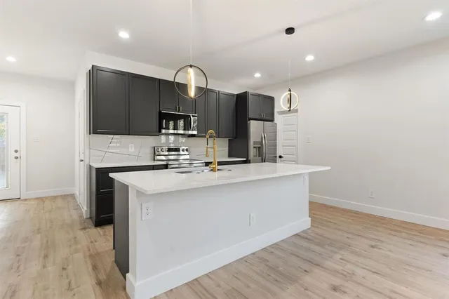 a kitchen with kitchen island stainless steel appliances a sink and a counter top space