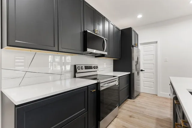 a kitchen with stainless steel appliances a stove microwave and refrigerator