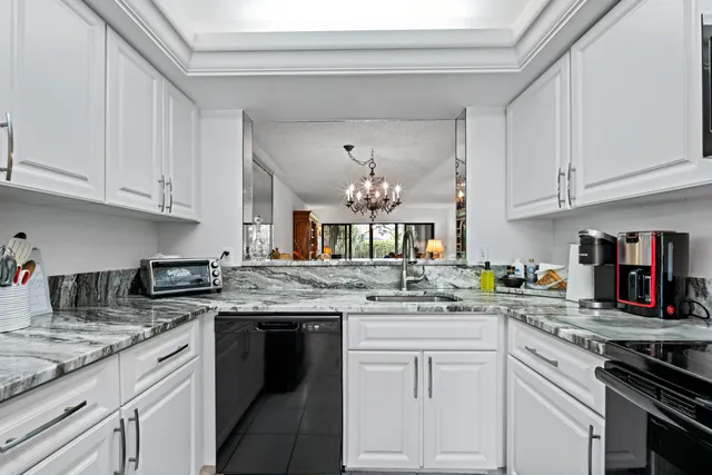 a kitchen with granite countertop a sink stainless steel appliances and white cabinets