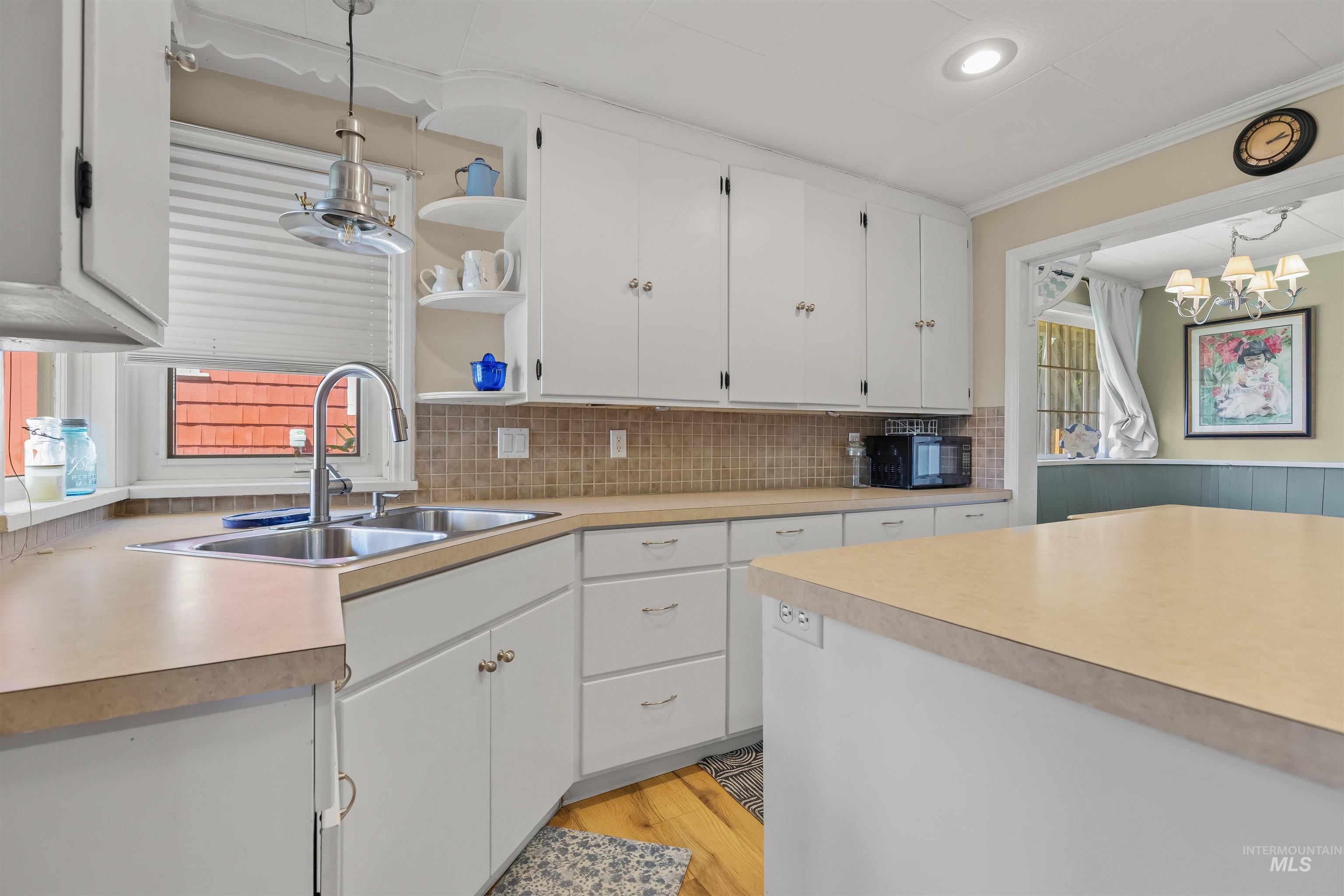 619 Prospect Avenue Lewiston, ID 83501 - Photo 12 of 37 Kitchen featuring white cabinetry, light-toned countertops, a stainless steel double sink with a gooseneck faucet, and a tiled backsplash