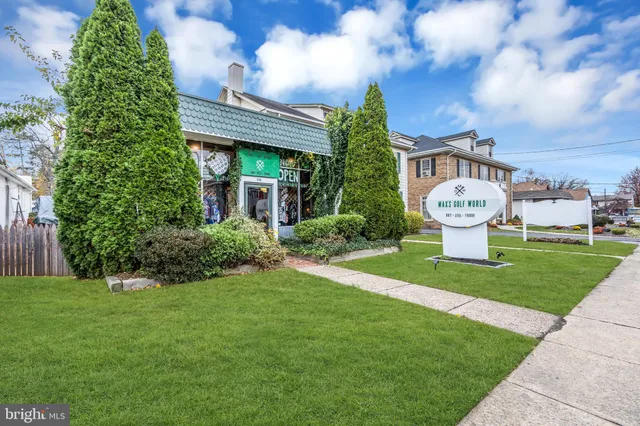 a view of a white house with a big yard and potted plants
