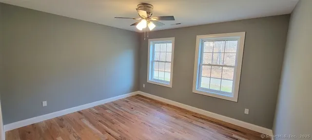 an empty room with windows and fan