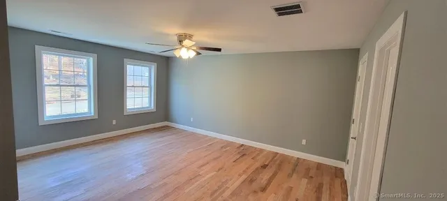 a view of room with window ceiling fan and hardwood floor
