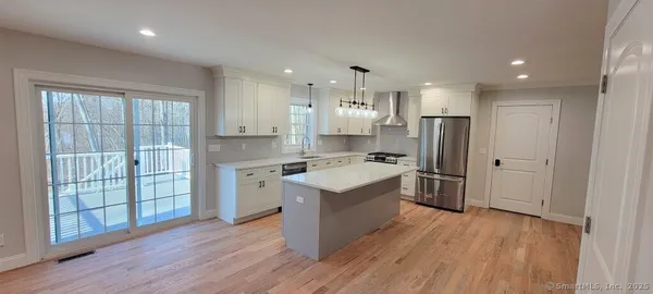 a kitchen with wooden floors and white stainless steel appliances