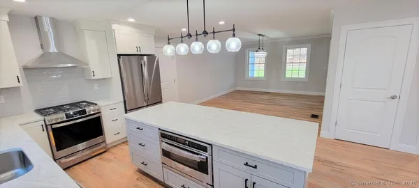 a kitchen with stainless steel appliances a stove a refrigerator and a wooden floor