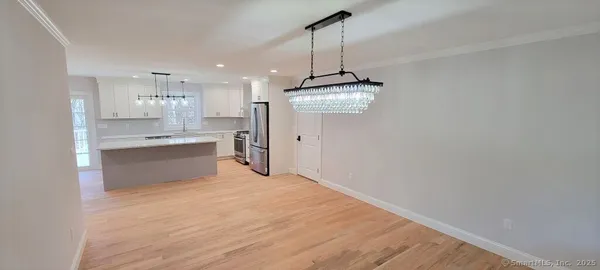 a view of a kitchen with a sink dishwasher refrigerator stove and a wooden floor