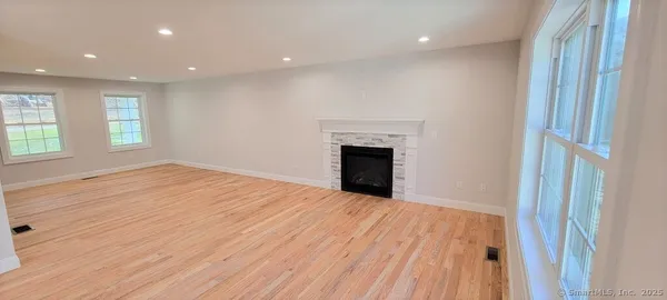 a view of empty room with wooden floor and fireplace