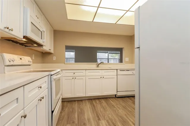a kitchen with granite countertop white cabinets and white appliances