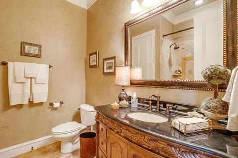 a bathroom with a granite countertop toilet sink and mirror