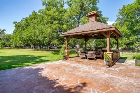 a view of backyard with table and chairs under an umbrella with a barbeque