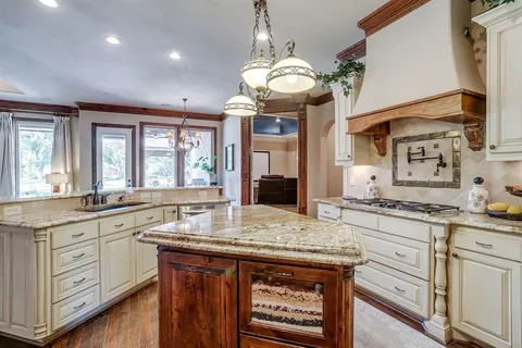a kitchen with granite countertop a sink a stove cabinets and wooden floor