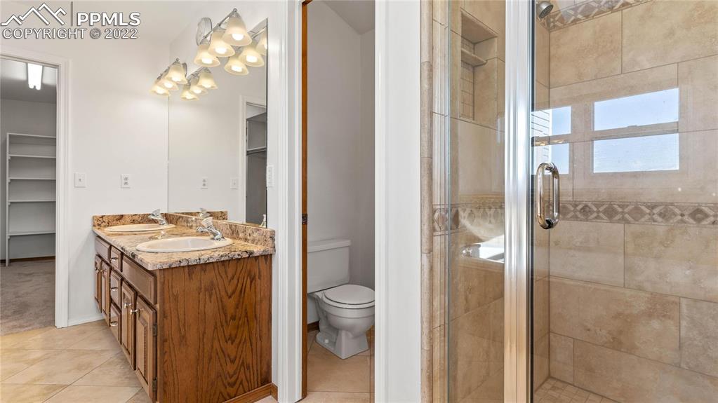 16250 Herring Road Colorado Springs, CO 80908 - Photo 22 of 50 a bathroom with a granite countertop sink a toilet and shower