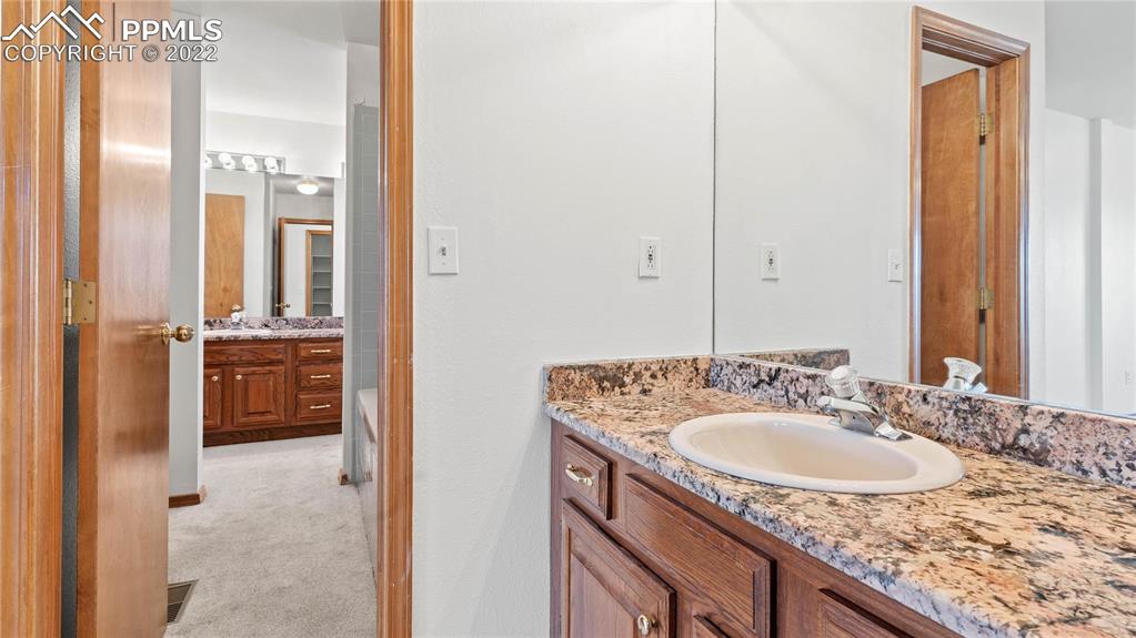 16250 Herring Road Colorado Springs, CO 80908 - Photo 29 of 50 a en suite bathroom with a granite countertop sink and a mirror
